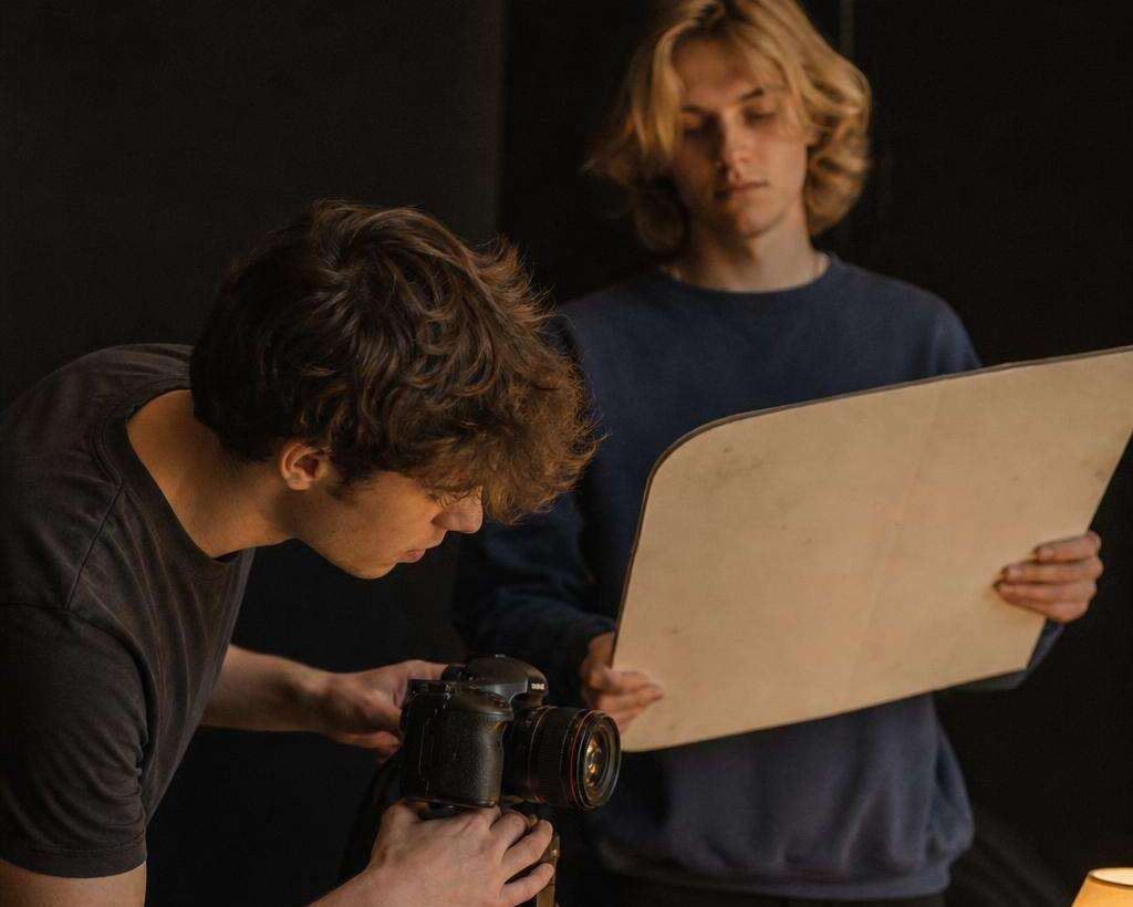 Two students with a camera and a reflector in a dark room